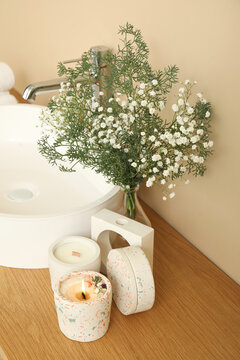 White sink, gypsophila flowers and candles on table in bathroom