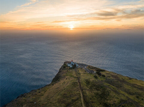 Aerial view of Ponta do Pargo Lighthouse on a steep cliff overlooking the Atlantic Ocean during a golden sunset Ponta do Pargo, Madeira, Portugal.