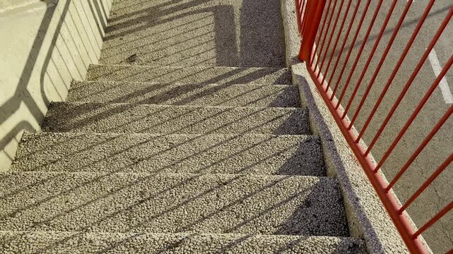 A staircase with steps made of Jerusalem stone and red railings in sunny weather.