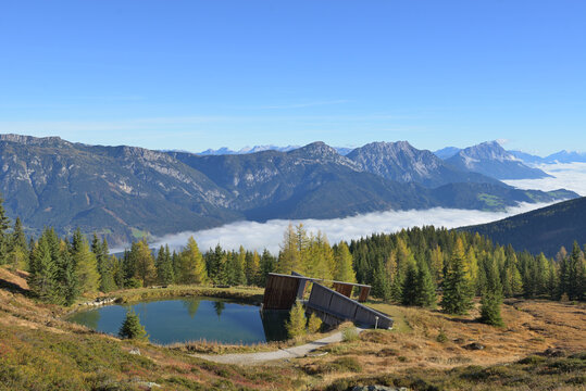 Planai water storage architecture for snowmaking overlooking alpine landscape and foggy valley Ennstal