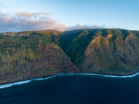 Aerial view of Miradouro do Ponta da Ladeira with steep cliffs and lush green hills overlooking the Atlantic Ocean in Porto Moniz, Madeira, Portugal.