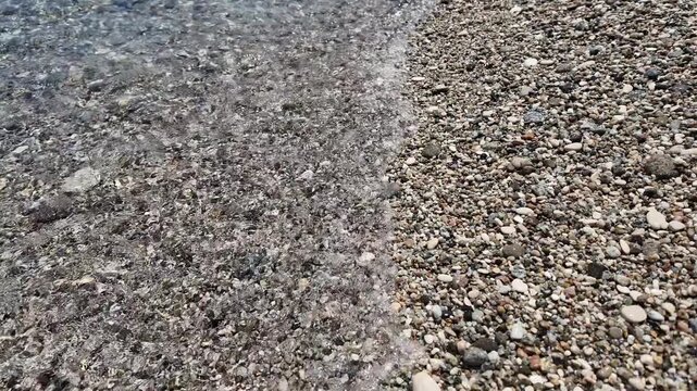 Crystal clear waves moving on pebble shore. Mediterranean coastline, natural texture and relaxation concept.