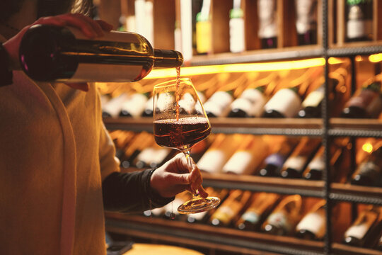 Woman Pouring Red Wine in Cozy Cellar