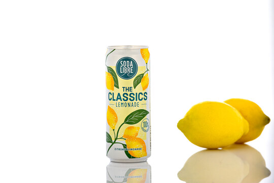 Soda Libre The Classics Lemonade can with fresh lemons photographed in studio on white background with reflection, highlighting natural citrus beverage concept.
