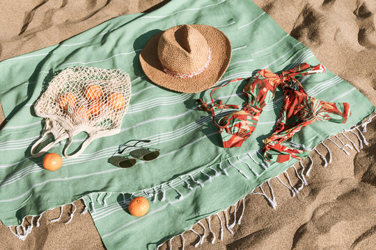 Hat, sunglasses, towel, bag, bikini on beach sand background. Summer vacation aesthetic concept. Sunbathing, beach party set, holiday picnic. Travel fashionable blog, social media. Flat lay, top view.