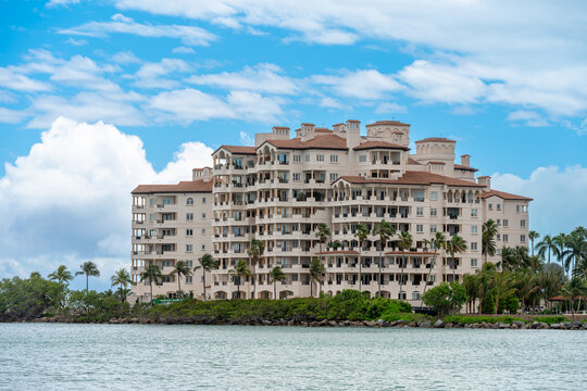 Luxury Waterfront Apartment Building on Fisher Island Miami. Multi-story Mediterranean style residential condominium building on the shore with palm trees.