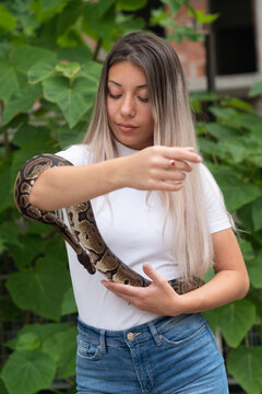 Young woman holding a python snake in an abandoned urban environment, wild concept