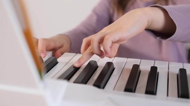 Child hands are pressing the white and black keys of a digital piano, learning musical notes and practicing their instrument in a bright, educational setting
