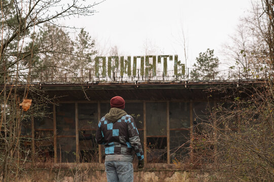Man looking at abandoned Pripyat sign in overgrown area