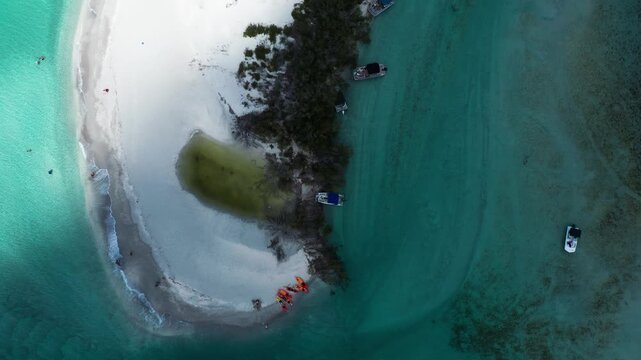 Boats float around a pristine sandbar with vibrant turquoise waters and lush vegetation. Ideal for travel and nature content.