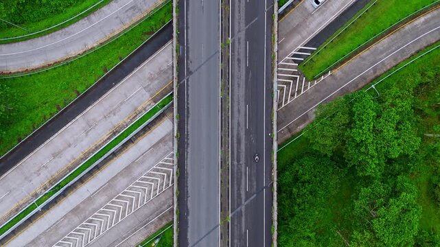 High-angle drone shot of multi-level road junction and overpass surrounded by tropical greenery