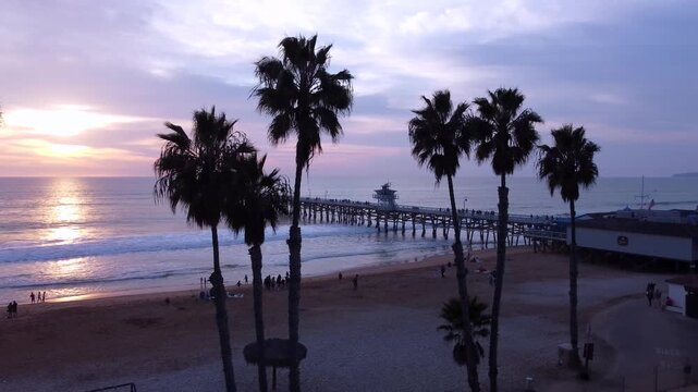 Pier Overlooking the Sunset on beach. San Clemente, Orange County, California. Cinematic Silhouette of Palm Trees in the foreground.