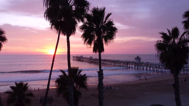 Pier Overlooking the Sunset on beach. Cinematic Silhouette of Palm Trees in the foreground. San Clemente, Orange County, California