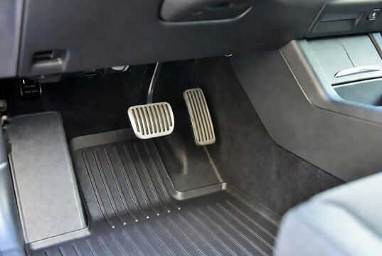 Interior of a Tesla Model 3 showing the footwell with mats and pedals.