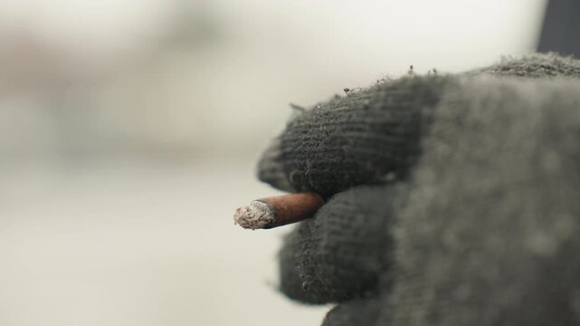 Smoking urban morning. Ember presses against foggy streets. Warm breath and gritty sunrise scene with cigarette tip. Flickering ember contrasts with misty urban streets and winter morning air