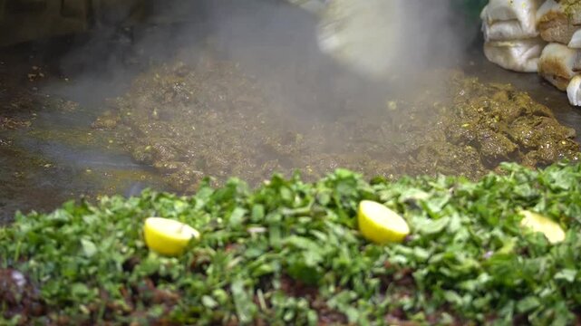 Kaleji with herbs and lemon cooking on sizzling street griddle, street food concept