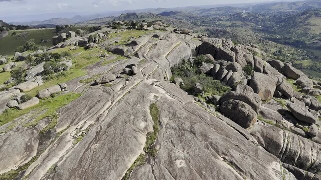 Drone flies up and away from rocky summit on a sunny day at Sibebe Rock near Mbabane, Eswatini