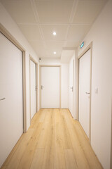 Obraz premium Un bureau, appartement neuf avec 5 portes fermées, les murs sont blancs et l'encadrement est en bois, le sol est un parquet en bois