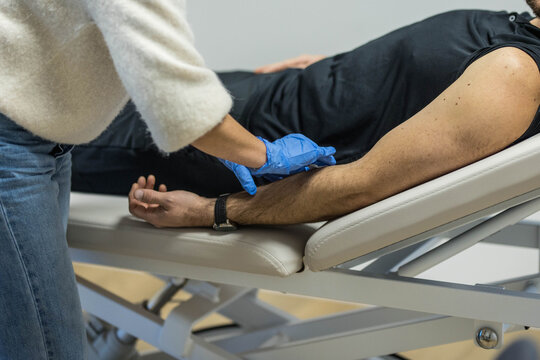 Une infirmi&egrave;re avec des gants bleus, nettoie le bras d'un patient avant une piq&ucirc;re et des soins