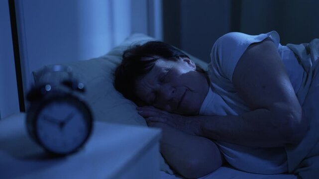 Elderly woman sleeping at night with clock nearby showing time