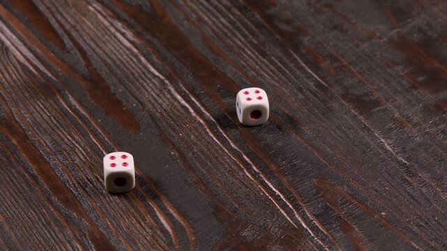 A close-up of a man's hand shuffling dice and then throwing them on the table, producing random values, then collecting them from the table