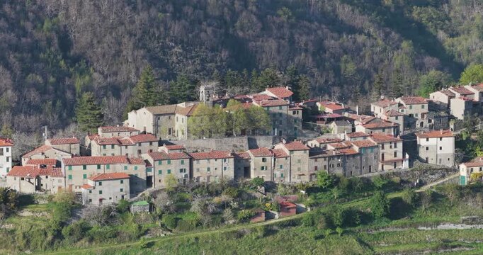 Aerial view of the historic stone houses and terracotta roofs of Trappola village nestled in the lush green hills of the Pratomagno area Trappola, Tuscany, Italy.