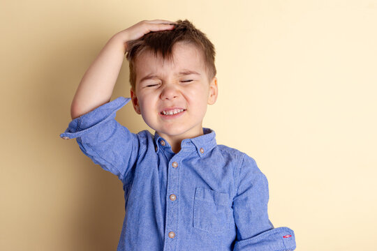 Boy of three years in a blue shirt on a yellow background. Emotional portrait.