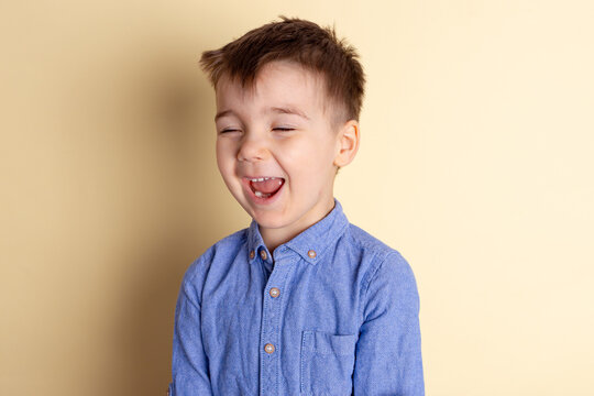 Boy of three years in a blue shirt on a yellow background. Emotional portrait.