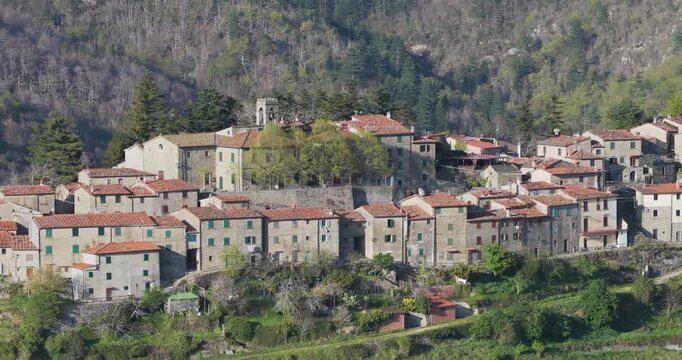 Aerial view of the historic stone houses and church tower of Trappola nestled in the lush green hills of the Pratomagno area, Trappola, Tuscany, Italy.