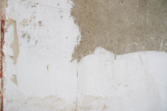 Textured wall with plaster and filler stains ready for finishing. Minimal composition highlights repair stage and building maintenance process.