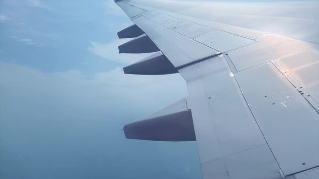 Airplane wing close up view from window seat flying above clouds, aerial travel video with blue sky background and copy space sky_008.