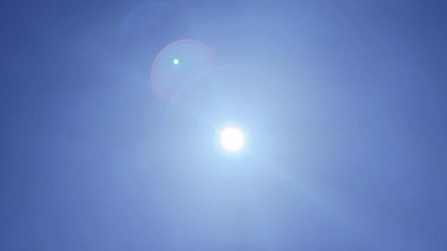 Bright sun with lens flare in clear blue sky timelapse, sunny day video background with sunlight and copy space sky_009