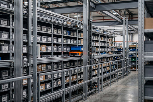 Magazzino automatizzato con robot su rotaia tra scaffalature piene di contenitori etichettati. Scena che rappresenta logistica avanzata, automazione e gestione intelligente dell&rsquo;inventario.