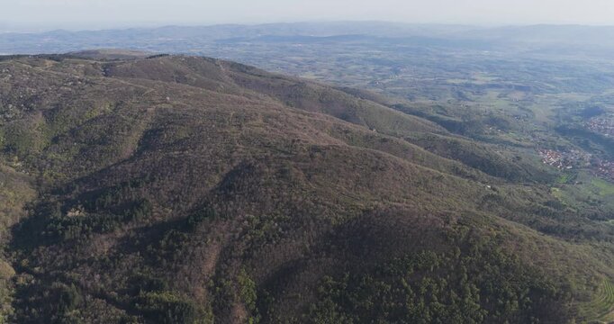 Aerial view of the lush green hills and dense forests of the Pratomagno mountain range under a clear sky in Trappola, Tuscany, Italy.