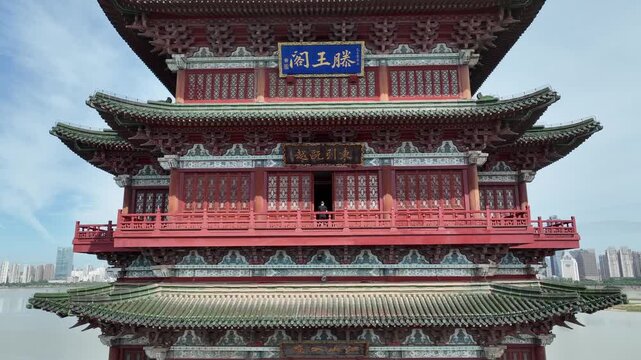 Drone aerial view of Tengwang Pavilion, a prominent traditional Chinese pagoda, gradually revealing intricate, historic architecture from aerial drone viewpoint, modern city skyline in background