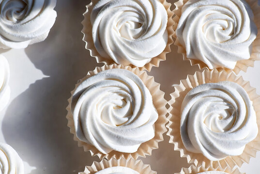 Subject: A stack of white-frosted cupcakes. Action: They are arranged on a surface, ready to be served. Setting: A light-colored table or countertop.