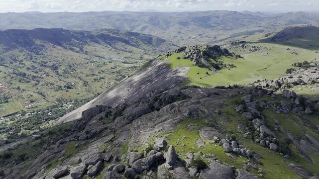 Drone descends on summit of Sibebe Rock with view of valley in the distance on sunny day near Mbabane, Eswatini