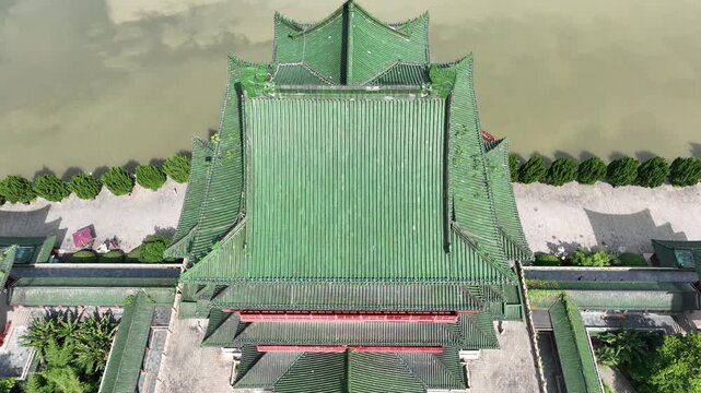 Aerial drone shot of Tengwang Pavilion, ancient Chinese architectural masterpiece, stands alongside Gan River, offering panoramic view of Nanchang city skyline merging history with modern development