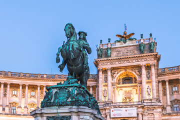 Obraz premium Night view of the illuminated Neue Burg wing of Hofburg Palace and Prince Eugene statue in Vienna.