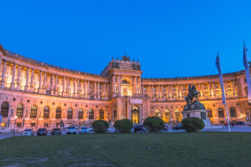 Obraz premium Night view of the illuminated Neue Burg wing of Hofburg Palace and Prince Eugene statue in Vienna.