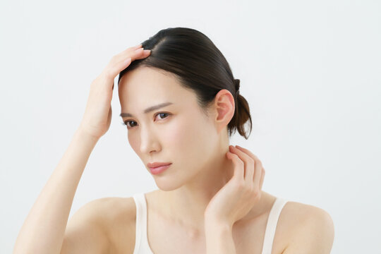 白背景の頭を触る若い日本人女性