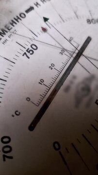 Macro shot of a classic analog barometer dial with a needle indicating atmospheric pressure. The gauge features a white face with black numbers and Russian text markings.