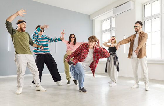 Modern indoor dance studio class, diverse group of dancing young people actively following trainer learning dance steps, team moving practicing choreography, feeling energized, improve technique 