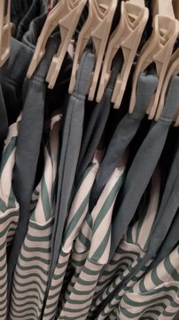 Matching sets of striped and solid-colored pajamas hang on a rack. Camera pans upward in a close-up shot, showing the texture of the fabric.