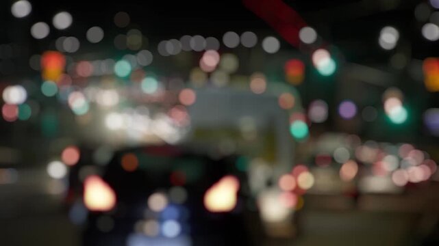 Vehicles travel along an urban road, lights diffused into soft shapes.