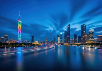 Obraz premium Illuminated skyline of a modern metropolis features a colorful tower and light trails over a river at dusk.