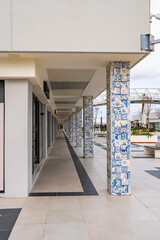 Obraz premium Contemporary walkway with decorative azulejo tile columns in Cascais, Portugal. Urban architectural scene with patterned ceramics, clean lines and coastal shopping area atmosphere.