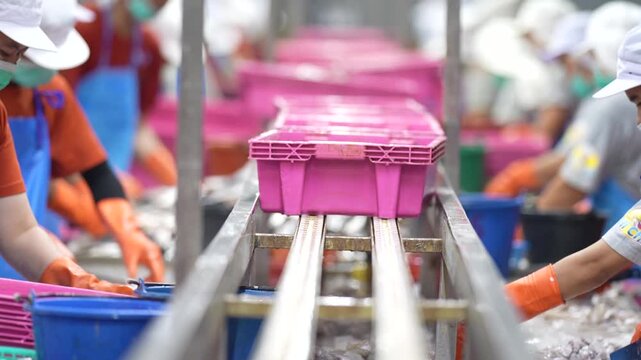 an empty automated conveyor belt system in a modern factory production line with blurred industrial workers in background.