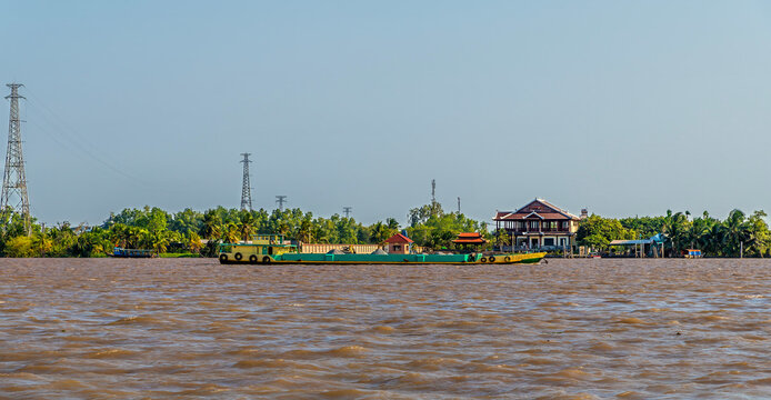 A view of a brightly coloured cargo barge on the Hau river near Can Tho in the Mekong Delta, Vietnam on a bright sunny day