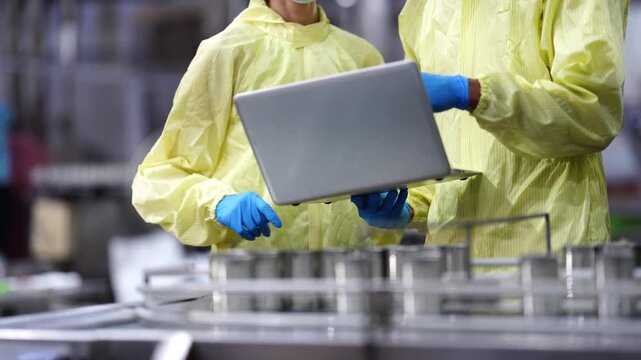 Diverse industrial professionals in protective suits and masks collaborating on technical data and operational audits in a modern smart factory facility.